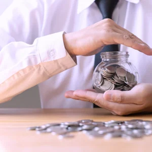 Person holding a jar with money inside, has their hand over the top, signifying protecting working capital