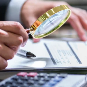 Hand holds a magnifying glass over documents, to dignify an accounts payable audit
