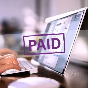 person on their laptop with an invoice on the screen. A purple paid stamp is over the top, to signify prompt payment