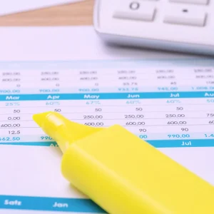 A highlighter pen lies on top of a supplier statement, alongside a calculator