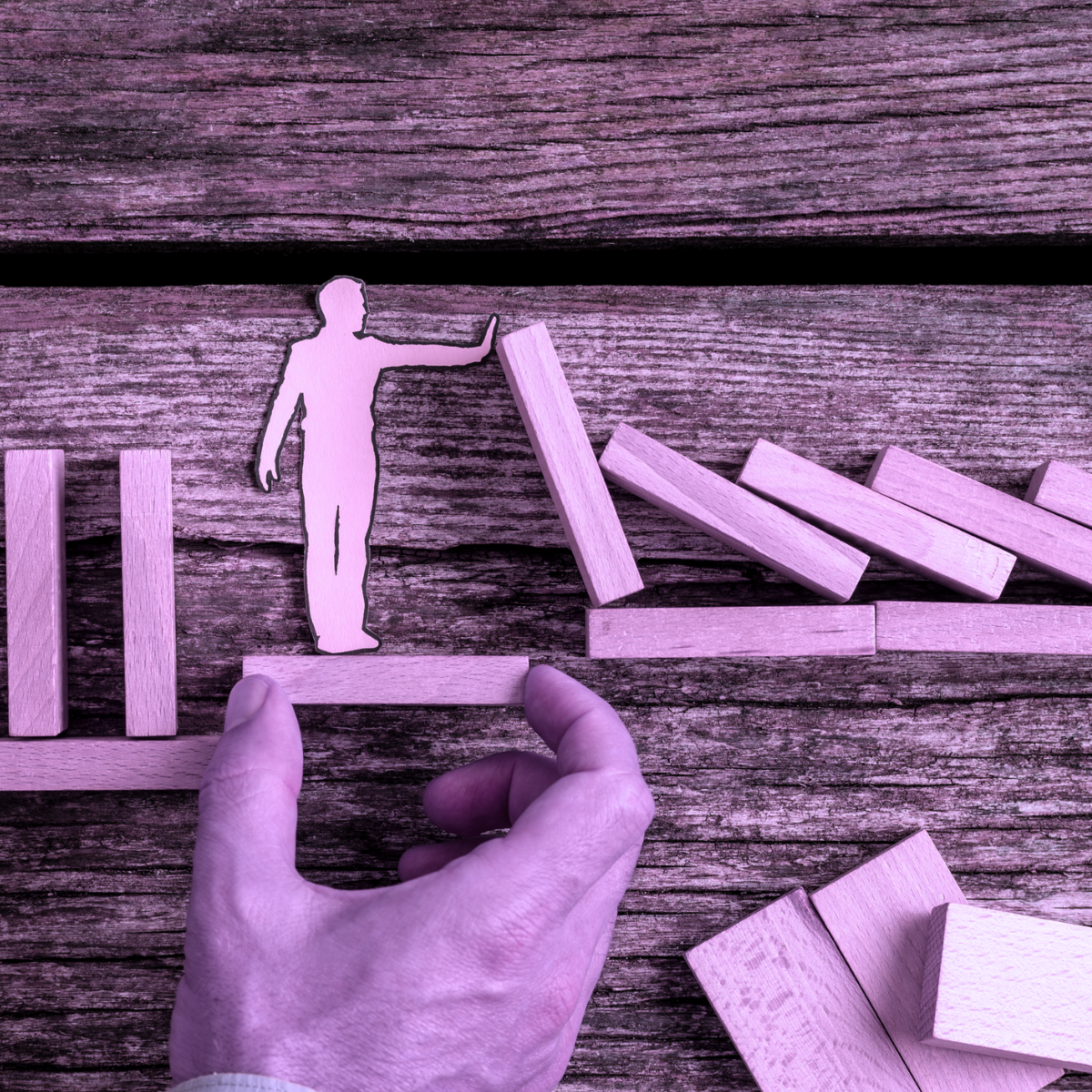A toy person halting falling wooden blocks, signifying the idea of no PO, no pay.